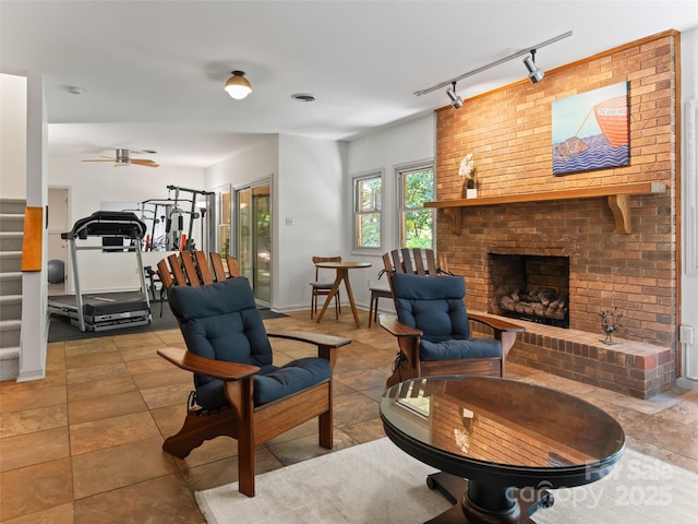 living room featuring stairway, a fireplace, a ceiling fan, and baseboards