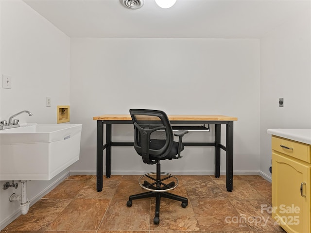 office area featuring stone finish flooring, visible vents, baseboards, and a sink