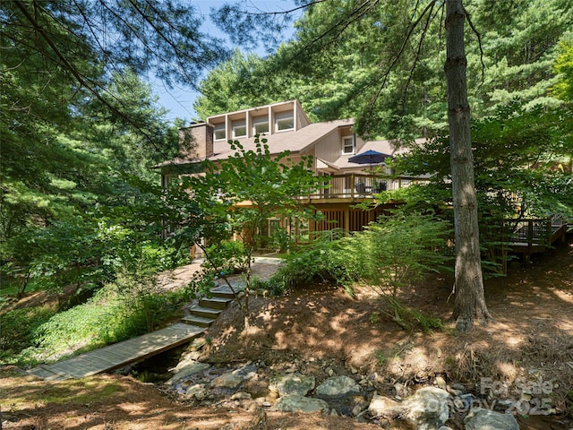 view of yard featuring a sunroom, stairs, and a wooden deck