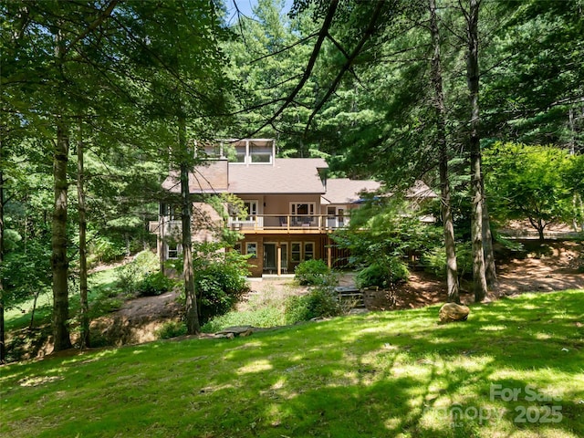 rear view of property featuring a lawn and a wooden deck