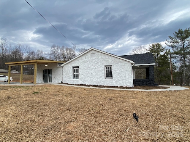 view of side of home with a lawn and roof with shingles