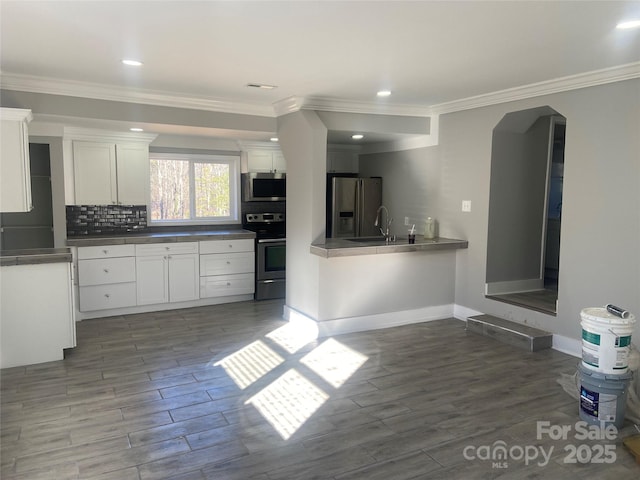 kitchen with arched walkways, dark wood-style flooring, white cabinetry, appliances with stainless steel finishes, and decorative backsplash