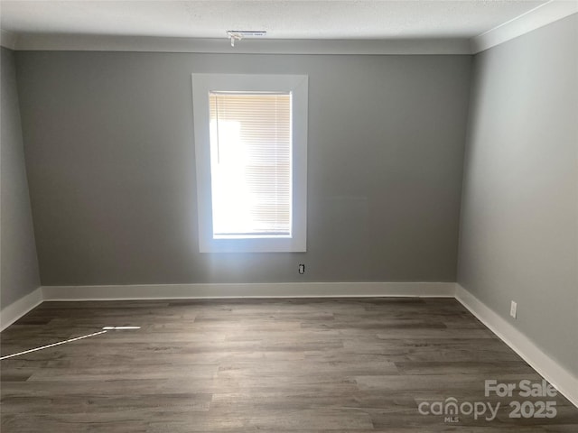 unfurnished room with a textured ceiling, baseboards, and wood finished floors