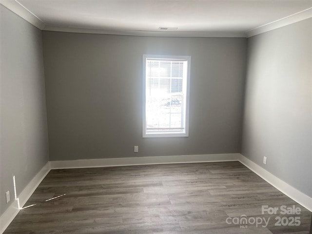 spare room with baseboards, visible vents, dark wood-style flooring, and ornamental molding