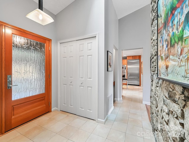 entryway featuring light tile patterned floors, high vaulted ceiling, visible vents, and baseboards