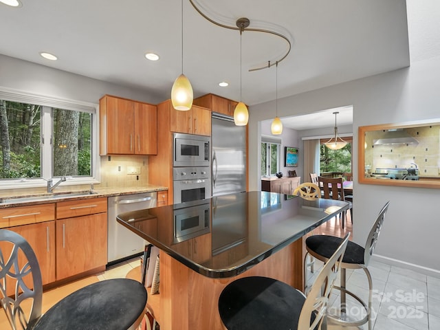 kitchen with built in appliances, extractor fan, light tile patterned flooring, a sink, and a kitchen breakfast bar