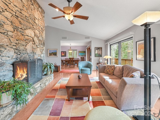 living room with a textured ceiling, wood finished floors, a fireplace, and lofted ceiling