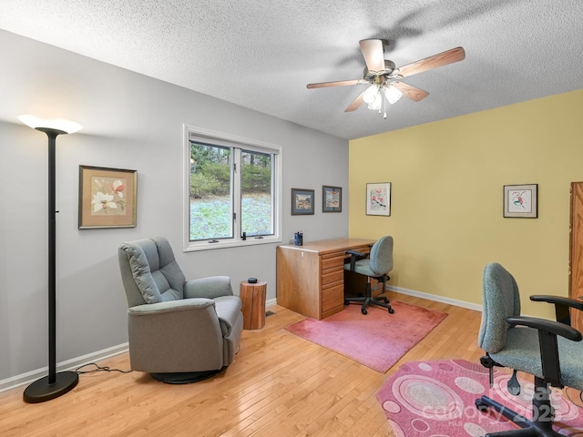 office with light wood-type flooring, a ceiling fan, baseboards, and a textured ceiling