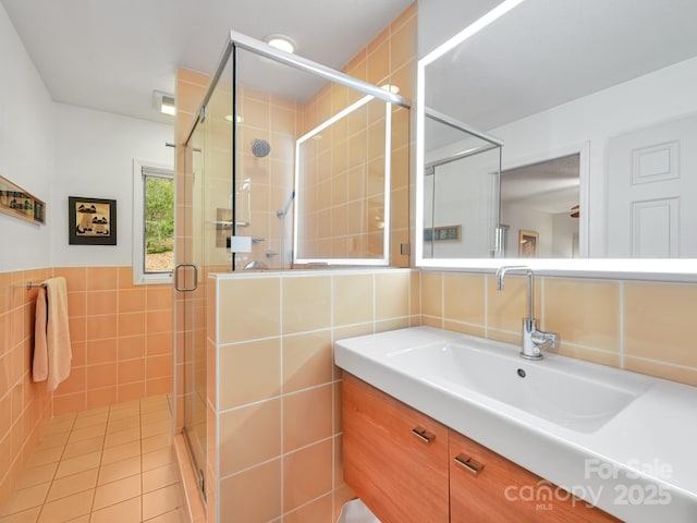 full bath featuring tile patterned floors, a shower stall, tile walls, and vanity