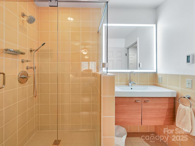 full bathroom with a stall shower, tile patterned floors, tile walls, and vanity