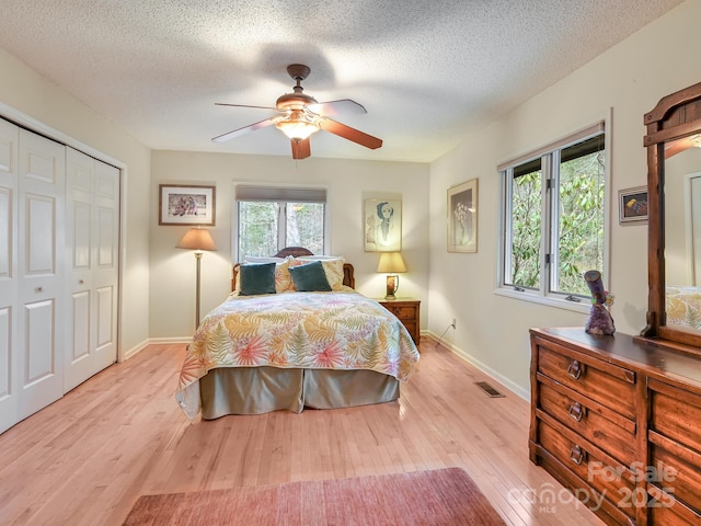 bedroom with baseboards, ceiling fan, a closet, and light wood-style floors