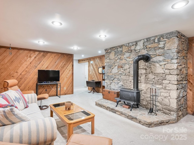 living area with carpet floors, recessed lighting, a wood stove, and wooden walls