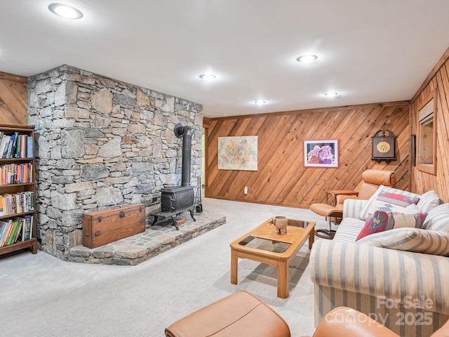 living room featuring carpet floors, recessed lighting, a wood stove, and wood walls