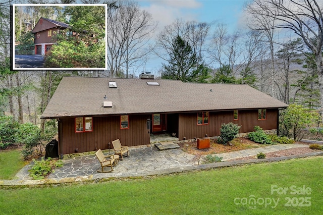 rear view of house featuring a yard, a patio, a chimney, and a shingled roof