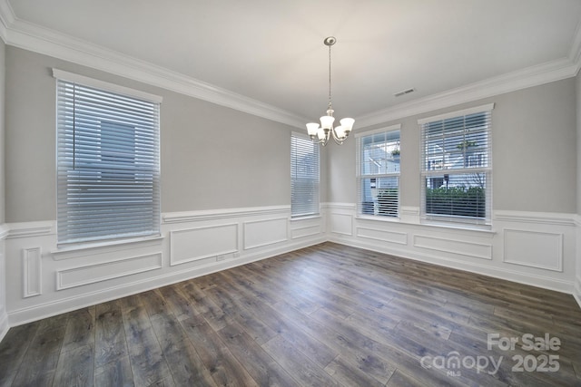 unfurnished dining area featuring a chandelier, crown molding, and dark wood finished floors