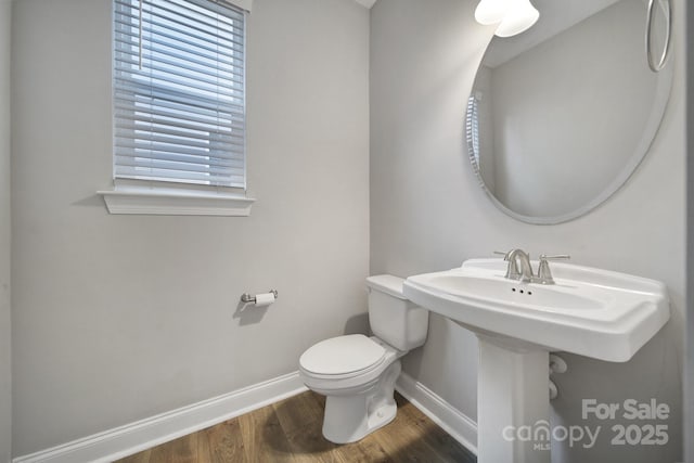 bathroom with toilet, baseboards, and wood finished floors