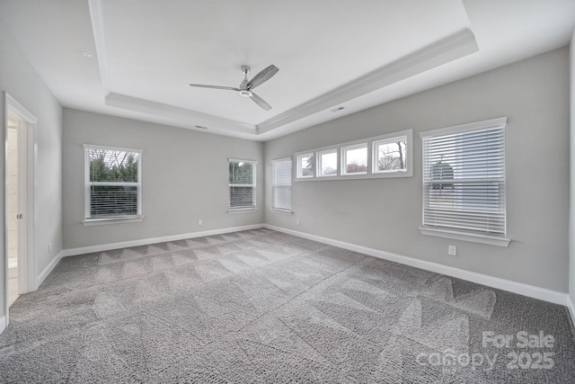 carpeted spare room featuring a ceiling fan, a raised ceiling, and baseboards