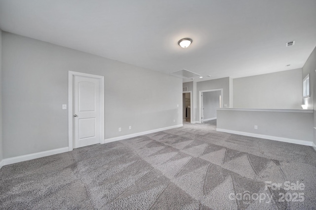 carpeted empty room with attic access, visible vents, and baseboards