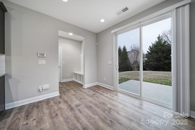 unfurnished room featuring plenty of natural light, wood finished floors, visible vents, and baseboards