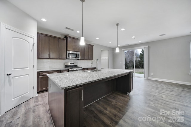 kitchen featuring stainless steel appliances, wood finished floors, a sink, visible vents, and decorative backsplash