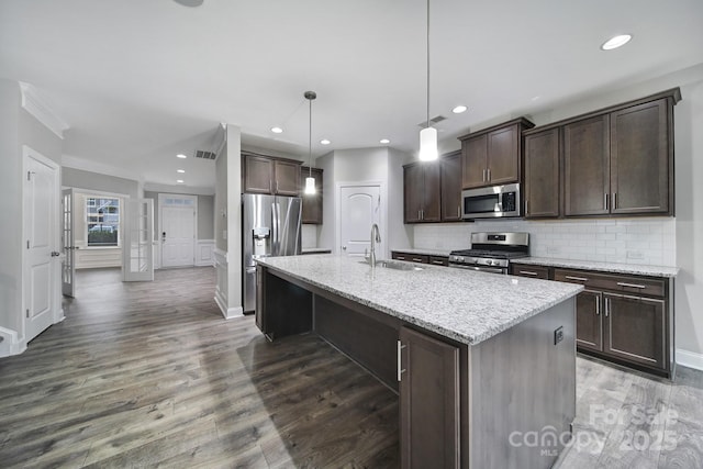 kitchen with dark brown cabinetry, wood finished floors, a sink, appliances with stainless steel finishes, and decorative backsplash