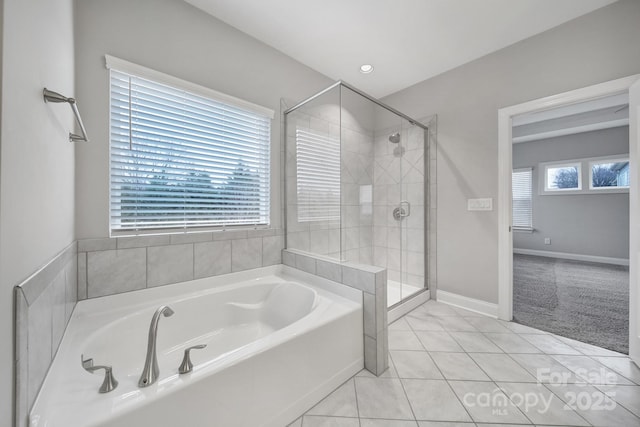 bathroom with tile patterned flooring, a shower stall, a bath, and baseboards