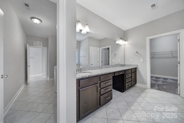 full bath featuring double vanity, a sink, baseboards, and tile patterned floors