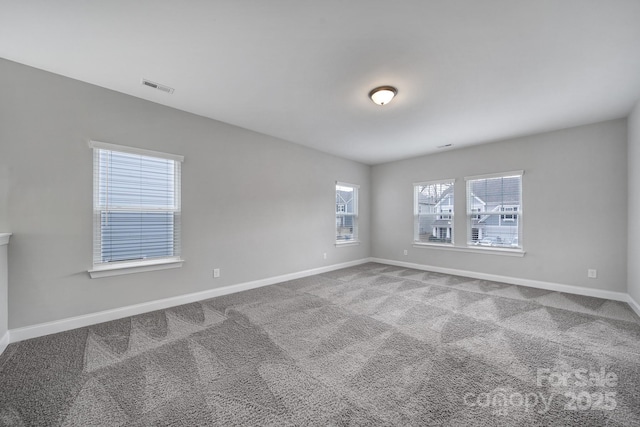 empty room with carpet floors, visible vents, and baseboards