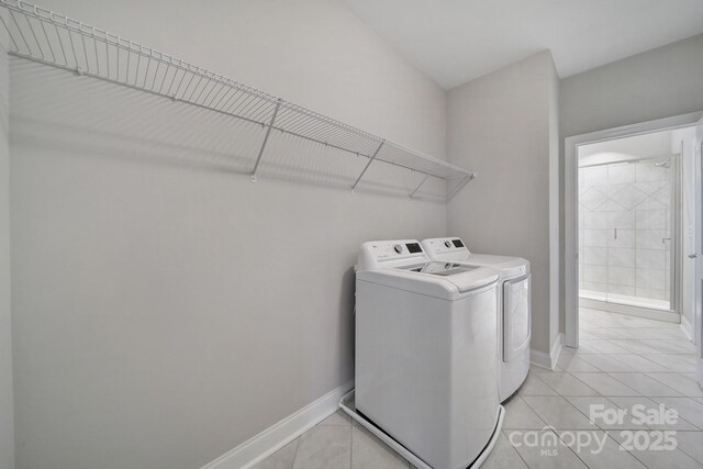 clothes washing area with light tile patterned floors, laundry area, washer and clothes dryer, and baseboards