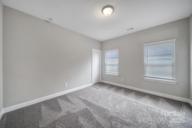 unfurnished room featuring baseboards, visible vents, and carpet flooring