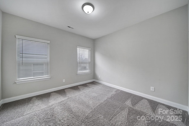 spare room featuring baseboards, visible vents, and carpet flooring