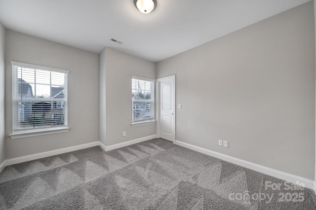 spare room with carpet, visible vents, plenty of natural light, and baseboards