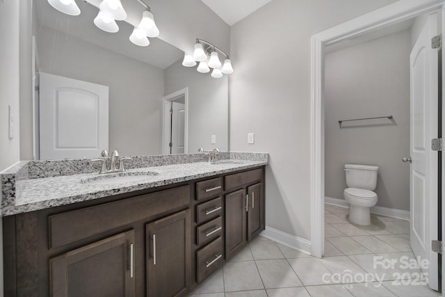 bathroom featuring double vanity, toilet, a sink, baseboards, and tile patterned floors