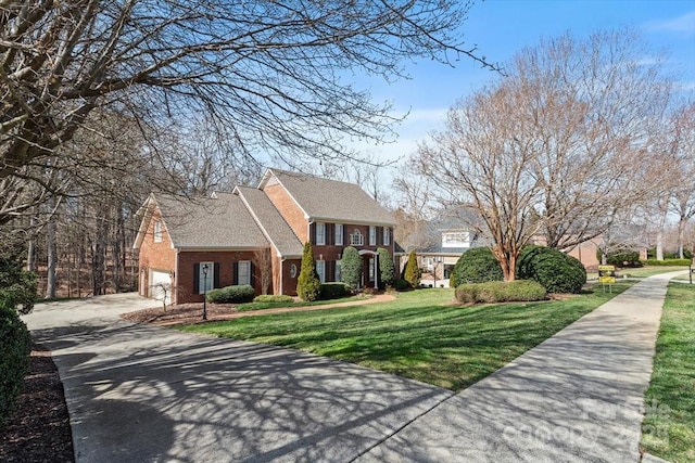 view of front facade featuring driveway, an attached garage, a front lawn, and brick siding