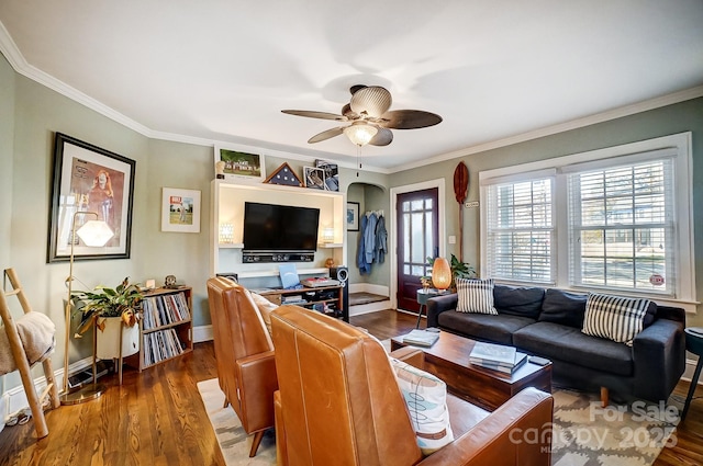 living area with baseboards, wood finished floors, a ceiling fan, and ornamental molding