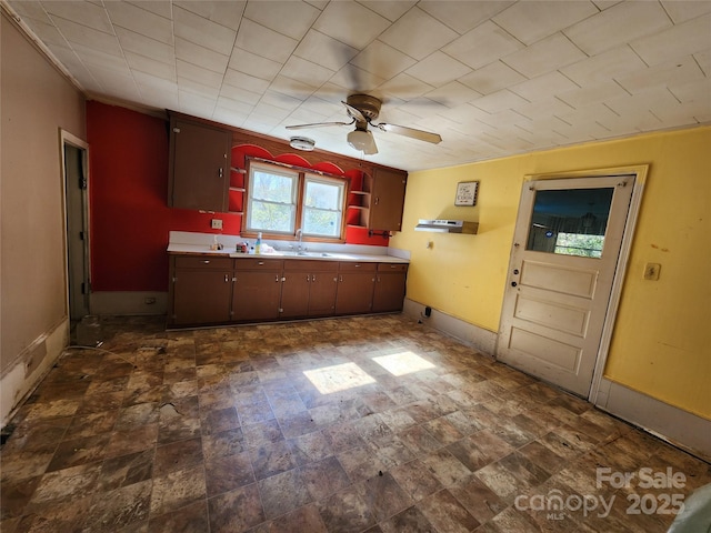 kitchen with open shelves, light countertops, ceiling fan, a sink, and baseboards