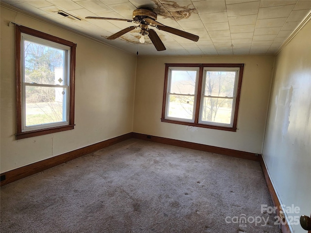 spare room featuring carpet flooring, crown molding, visible vents, and baseboards