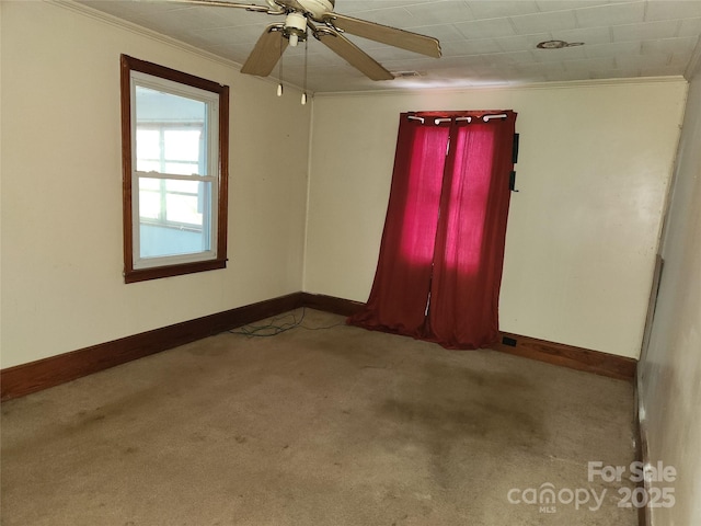 empty room with ceiling fan, baseboards, crown molding, and light colored carpet