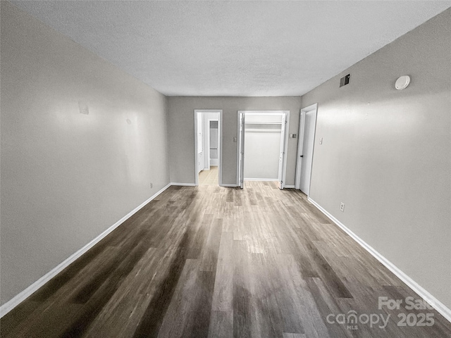 unfurnished living room featuring dark wood-style floors, visible vents, baseboards, and a textured ceiling