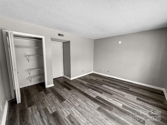 unfurnished bedroom with a closet, dark wood-style flooring, visible vents, and baseboards