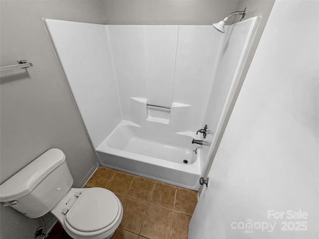 bathroom with washtub / shower combination, tile patterned flooring, and toilet