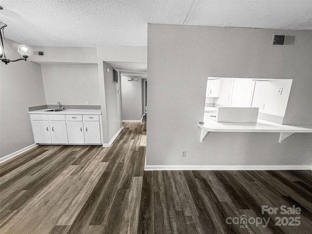 kitchen featuring dark wood-style floors, a sink, visible vents, and white cabinetry