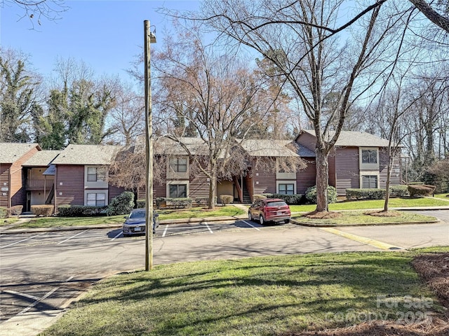 view of front facade with uncovered parking and a front lawn