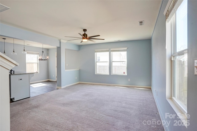 empty room featuring visible vents, carpet floors, baseboards, and ceiling fan with notable chandelier