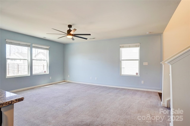 carpeted spare room with visible vents, baseboards, and ceiling fan