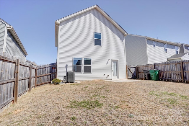 rear view of house with a fenced backyard, central AC, and a yard