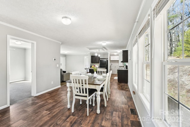 dining room featuring dark wood finished floors, visible vents, ornamental molding, a textured ceiling, and baseboards