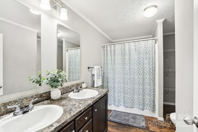 full bath with double vanity, crown molding, a sink, and wood finished floors