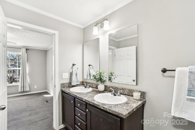 bathroom with a textured ceiling, double vanity, ornamental molding, and a sink