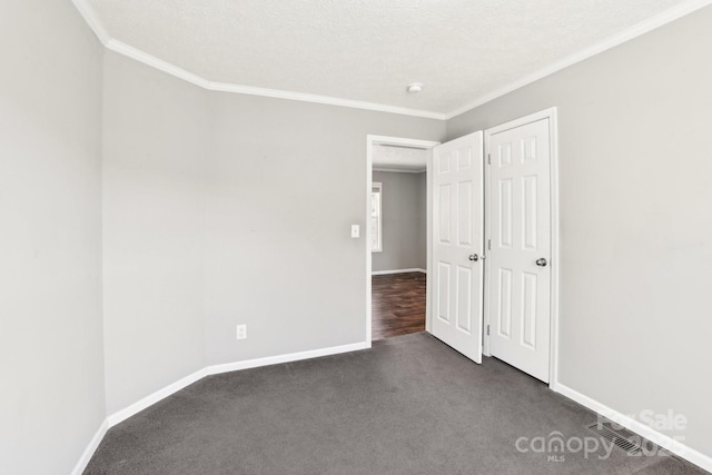 unfurnished bedroom featuring baseboards, visible vents, dark colored carpet, a textured ceiling, and crown molding